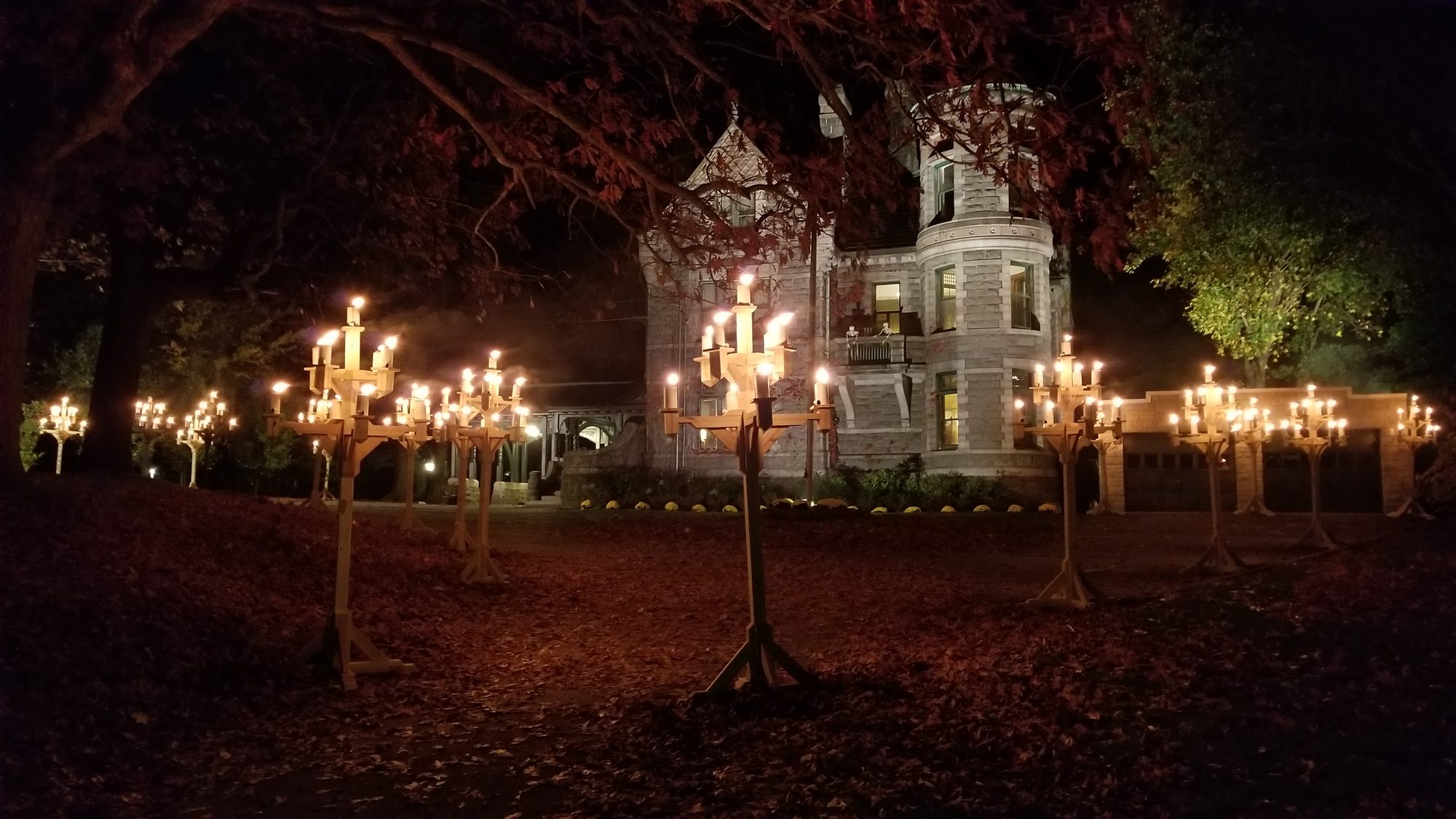 Nine-foot candelabras burning on the lawn at night with the floodlit castle behind